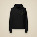 Sweat à capuche femme noir brodé du monogramme RS, vue de face sur fond pierre — Maison Sahari